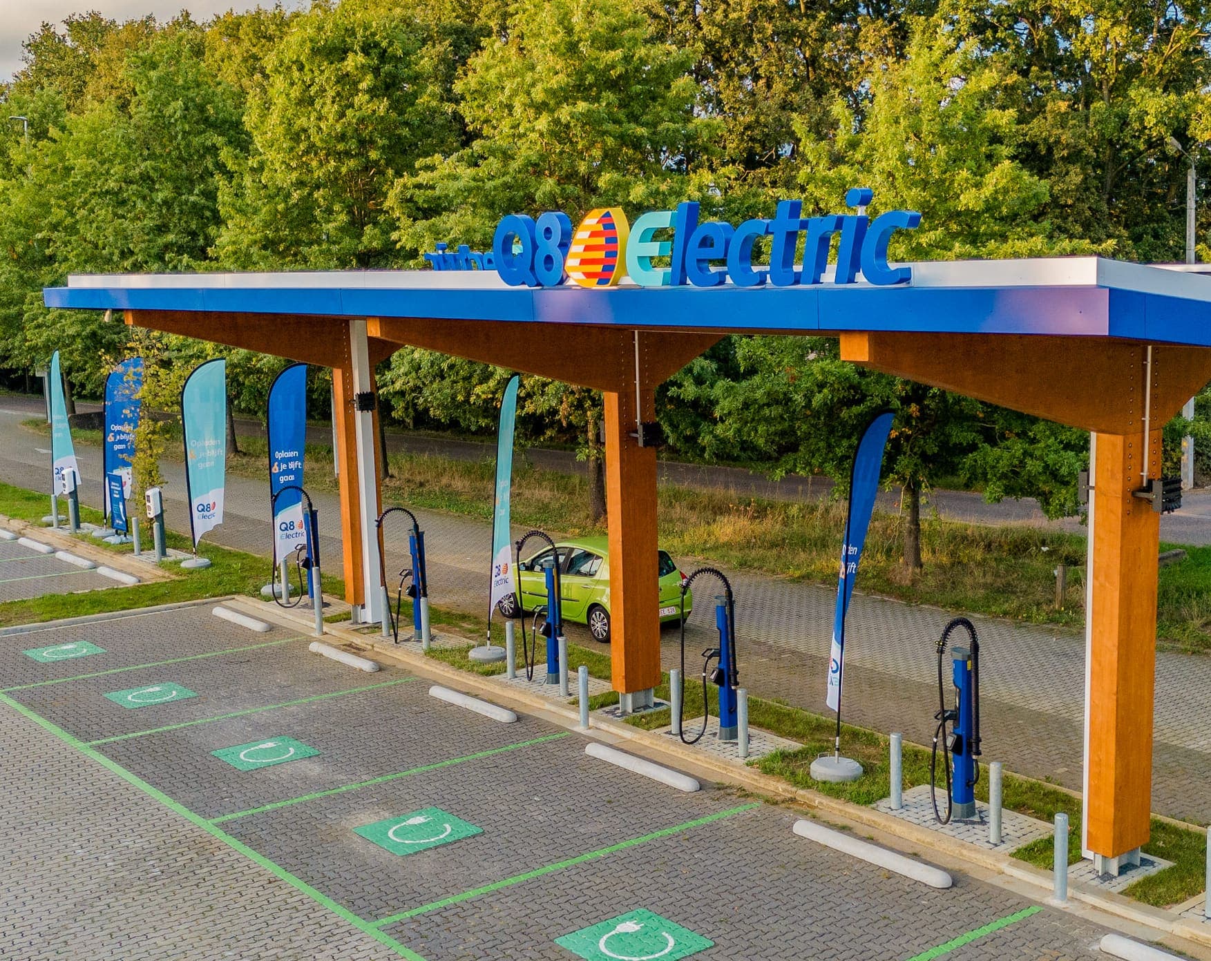 A Q8 electric charging plaza: charge points and marked bays under a blue canopy.